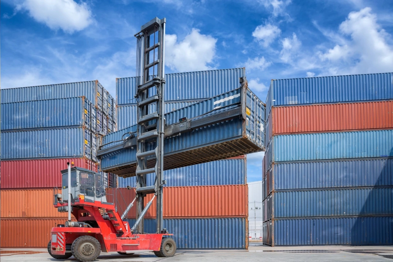 A red forklift is parked in front of some blue containers.