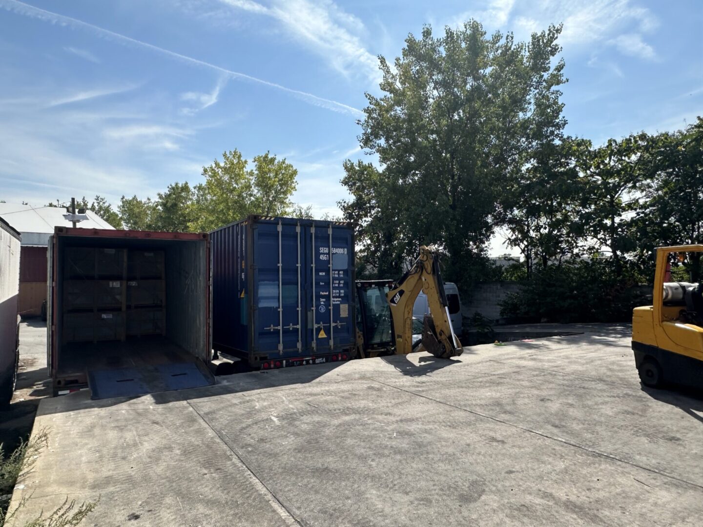 A man in yellow jacket standing next to a blue container.